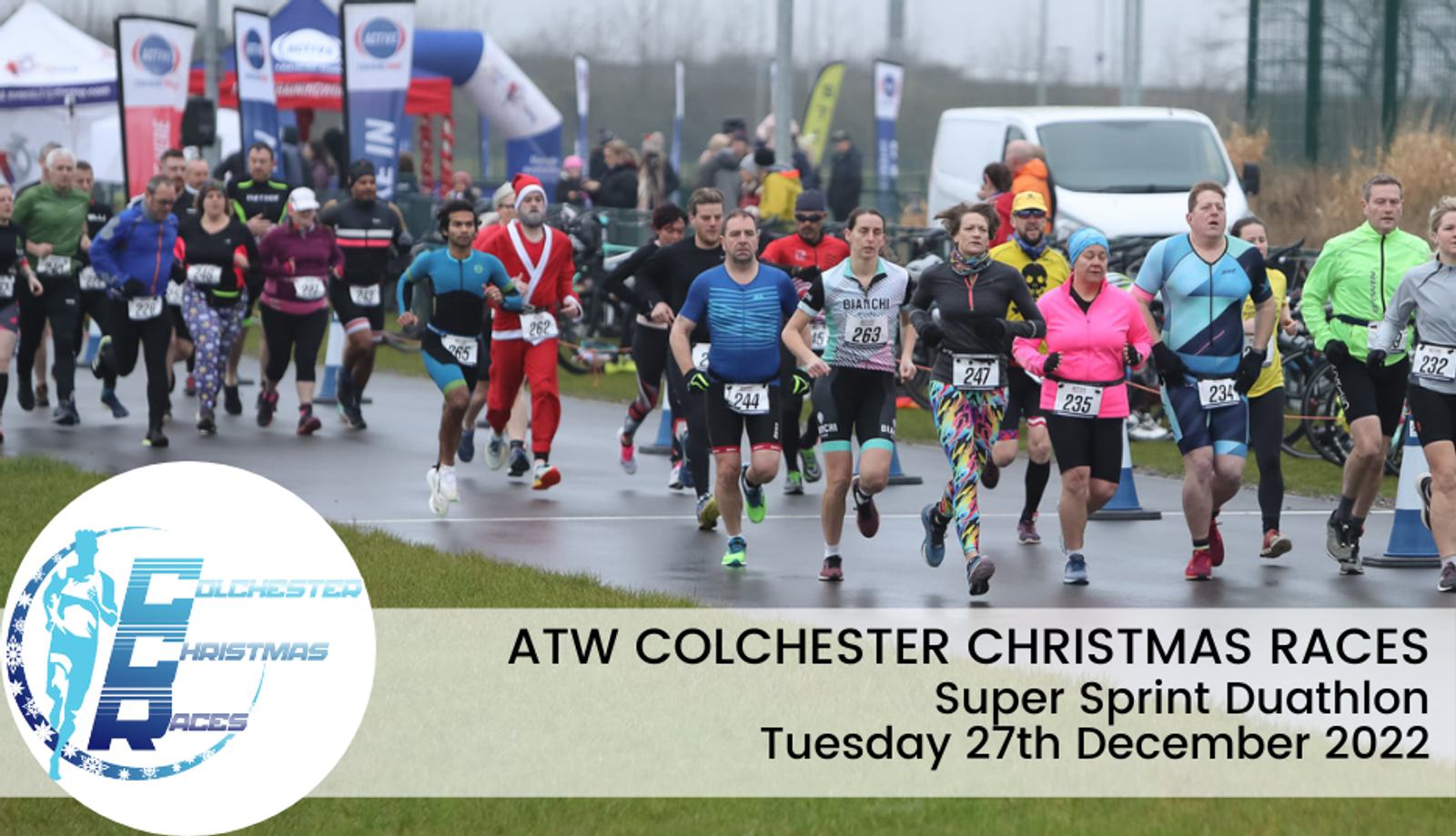 A group of athletes running in an outdoor winter race event. Participants are dressed in various athletic gear and some festive outfits. A banner on the left reads "ATW Colchester Christmas Races." The event is the Super Sprint Duathlon on December 27, 2022.