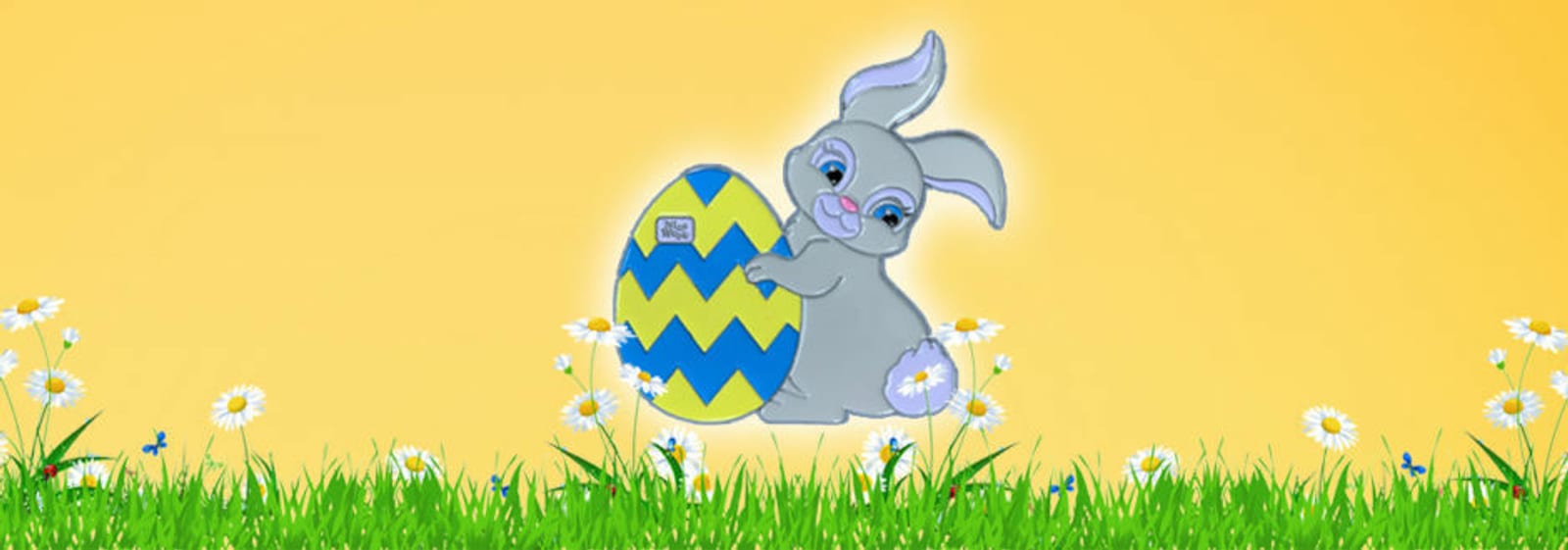 A cute cartoon bunny with a fluffy tail holds a large, decorated Easter egg with blue and yellow zig-zags in a field of green grass and white daisies against a bright yellow background.