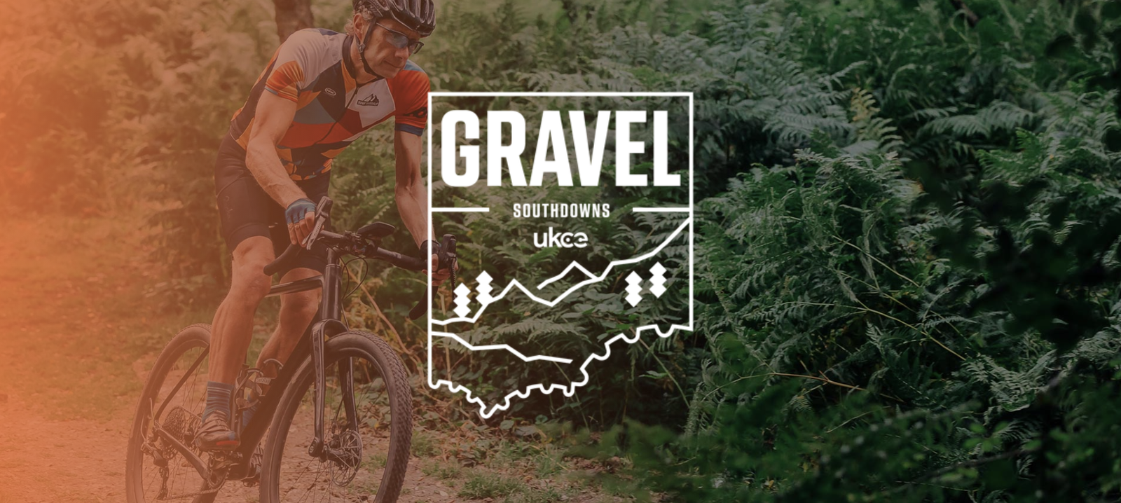 A cyclist wearing a helmet and sports attire rides a gravel bike on a dirt path through lush green ferns. The image has an overlay featuring the event name "Gravel Southdowns" and the UKCE logo at the center.