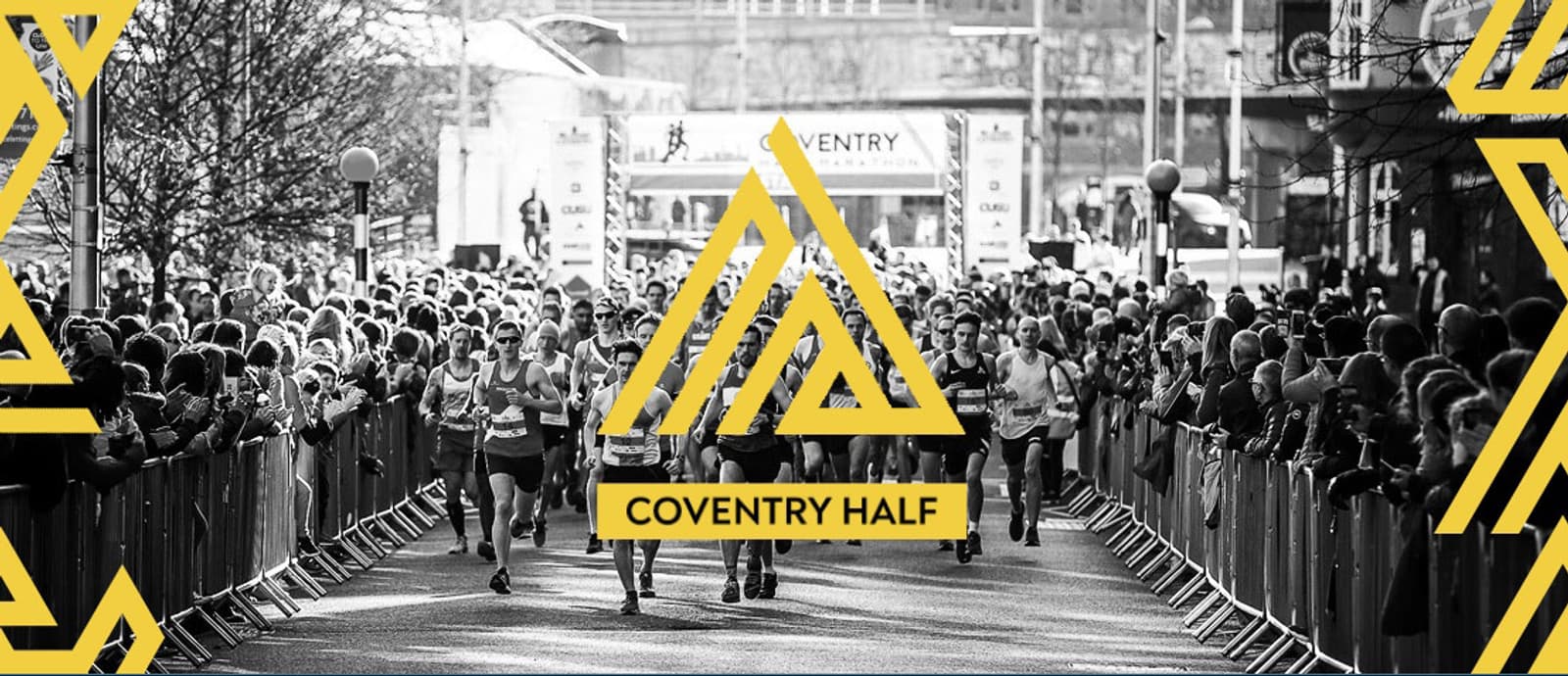 Black and white image of a large crowd of runners participating in the Coventry Half Marathon. Spectators line the streets cheering behind barriers. The event's logo and the words "COVENTRY HALF" are prominently overlayed in yellow.