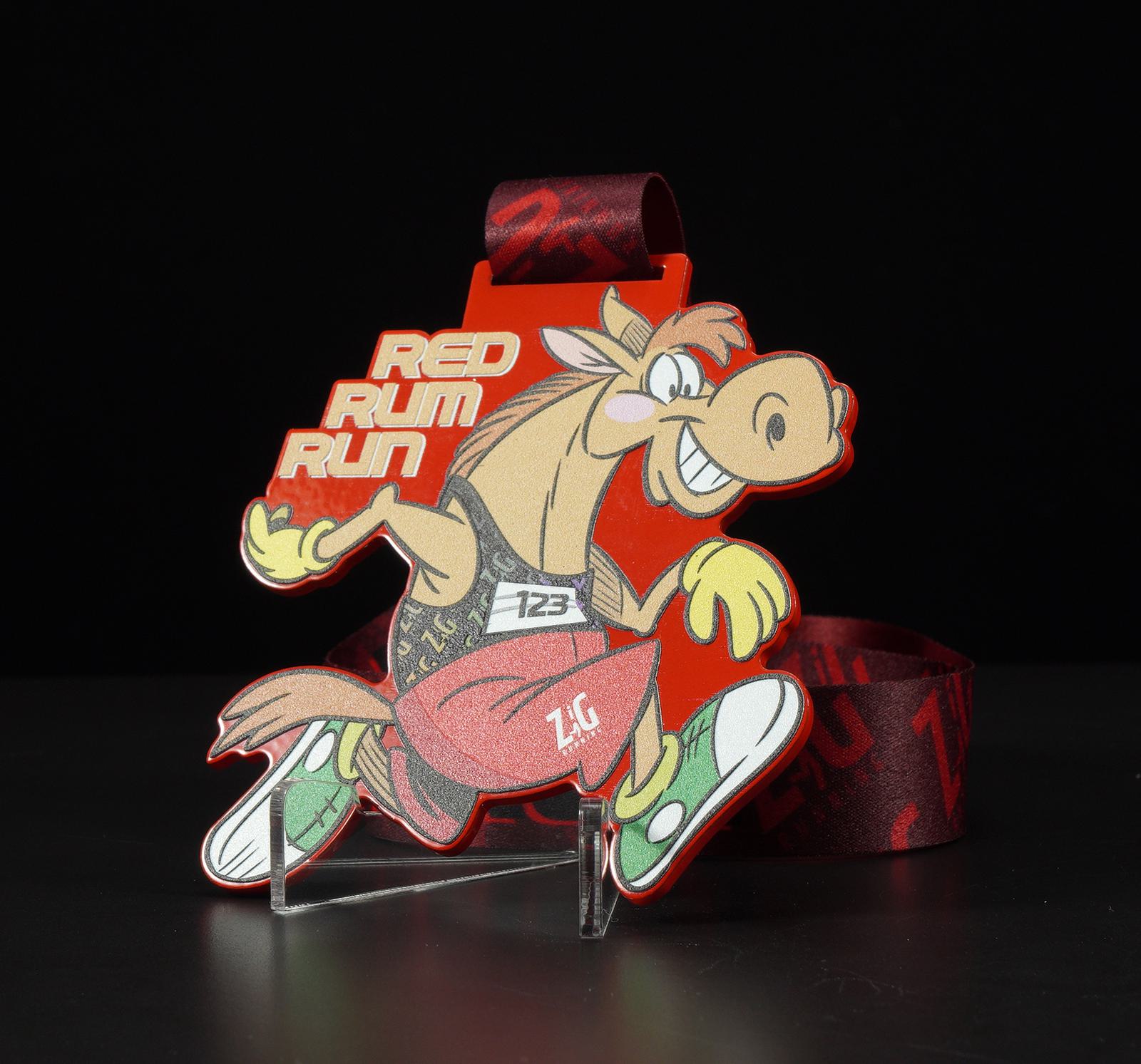 A medal with a cartoon horse running, smiling, and wearing a race bib with the number 123. The horse is brown with white detailing and dressed in a red and black outfit. The medal has "Red Rum Run" written in bold red letters. The ribbon is dark red with subtle patterns.