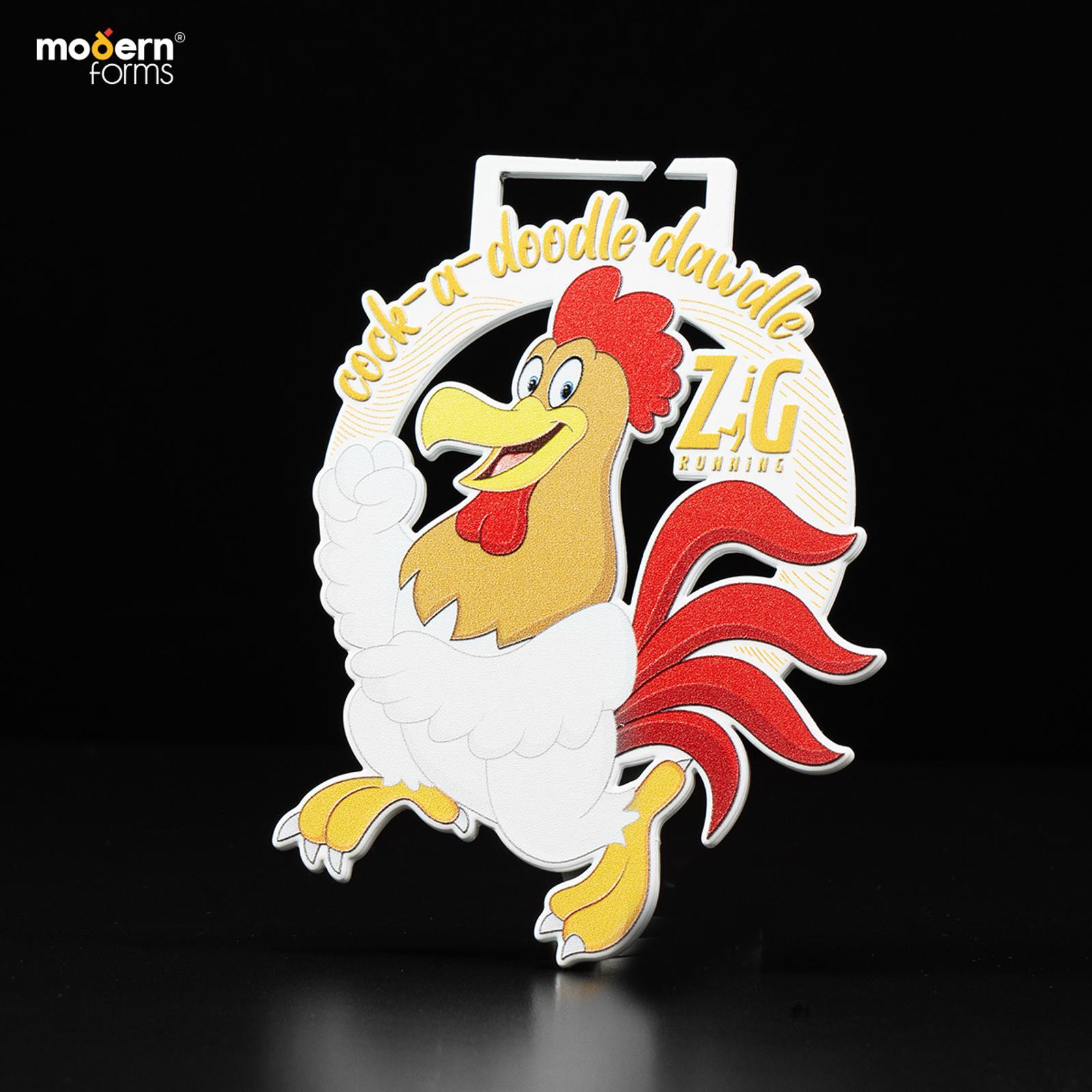 A cartoon rooster medal design with the phrase "cock-a-doodle doo" in yellow above it. The rooster is smiling with one hand raised. The medal has a circular handle at the top. The background is black.