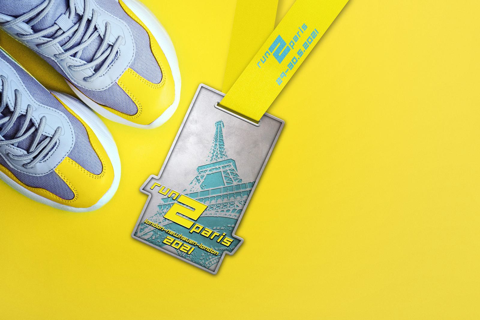 A pair of grey and yellow running shoes next to a medal with "run 2 paris 2024" inscribed on it, featuring an image of the Eiffel Tower. The medal is attached to a yellow ribbon that reads "run 2 paris" and "29.09.2024". The background is a solid bright yellow.