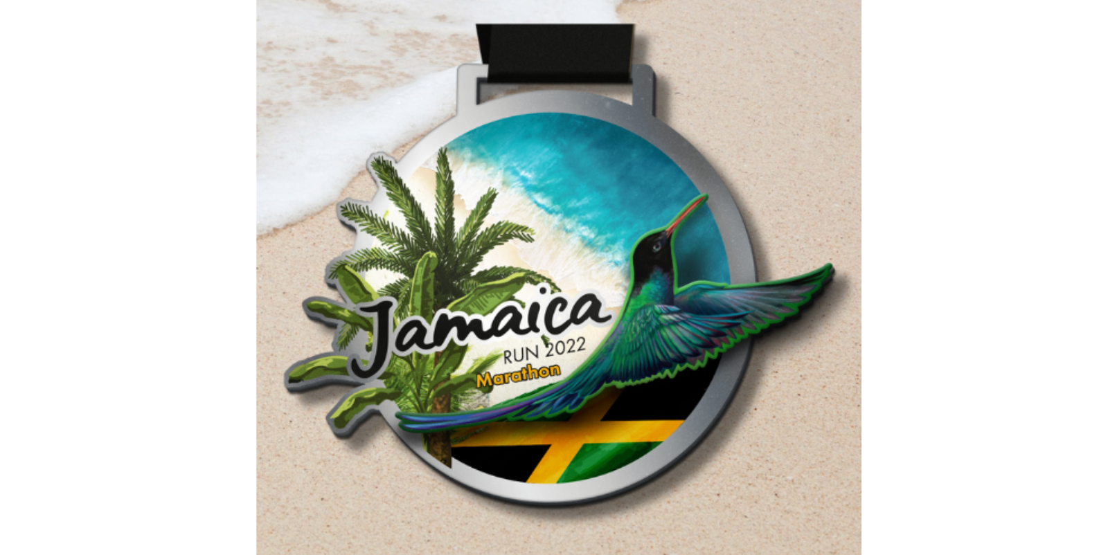 A round medal with a tropical design features the text "Jamaica Run 2022 Marathon." It shows a palm tree, a vibrant hummingbird, the Jamaican flag, and a blue sky background. The medal is placed on a sandy beach.