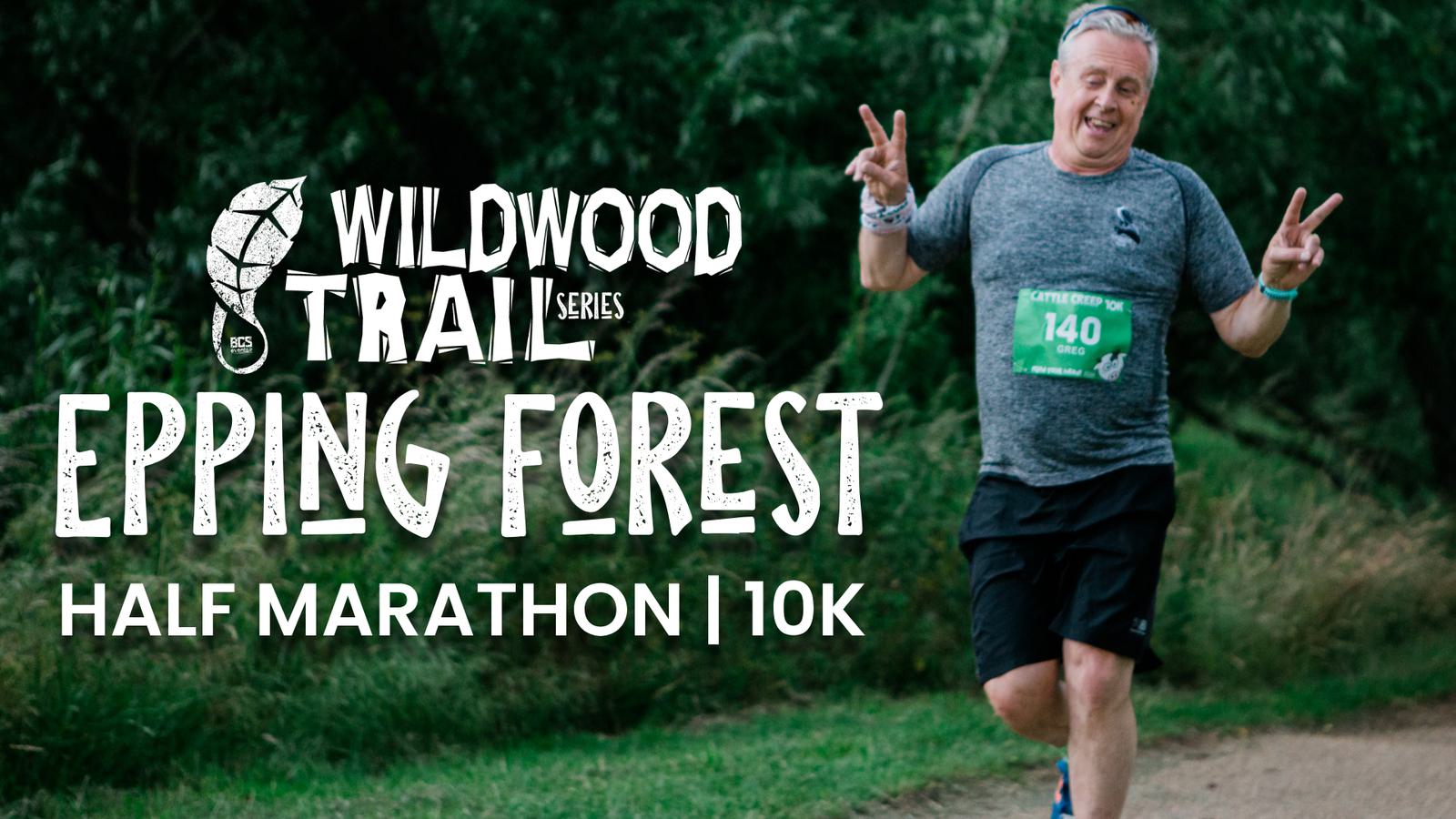 A man in athletic attire runs on a trail, smiling and showing peace signs with both hands. He wears a green race bib numbered 140. The background features lush greenery. Text reads "Wildwood Trail Series Epping Forest Half Marathon | 10K.