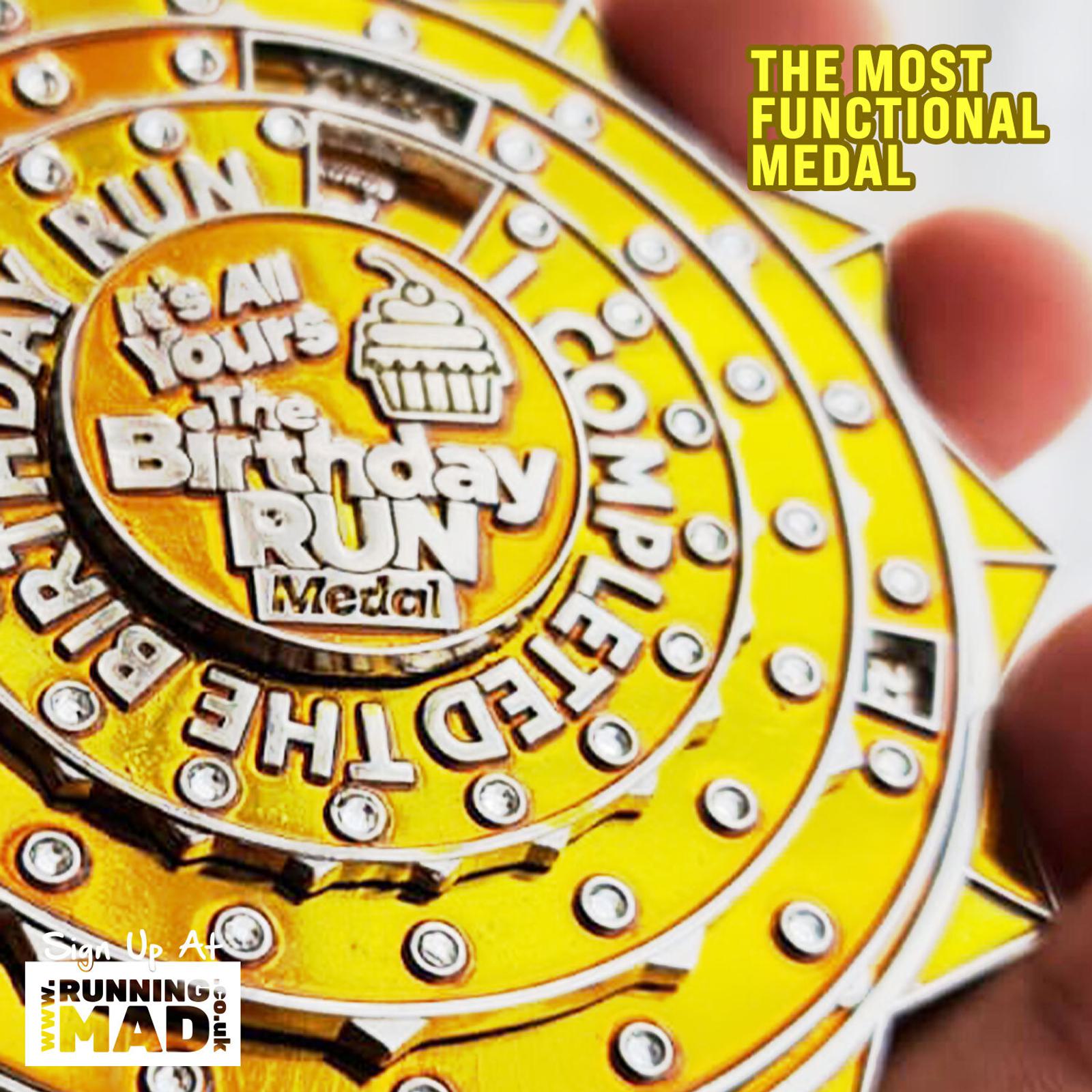 Close-up of a golden medal with a cupcake design in the center. Text on the medal reads "The Birthday Run" and "Completed." Additional text in the top right corner says "The Most Functional Medal." Logo at the bottom left reads "Running Mad.