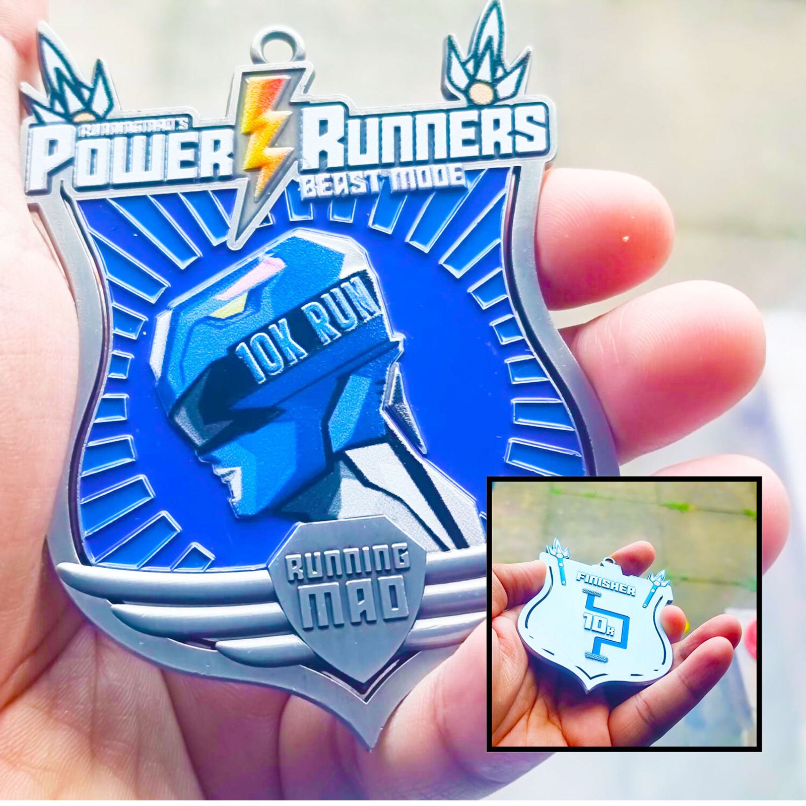 A person holds a medal featuring the text "Power Runners Beast Mode" with a blue figure and "10K Run" on it. An inset shows the back, marked "FINISHER TOP 1%." The medal has a futuristic design with wings and lightning bolts.
