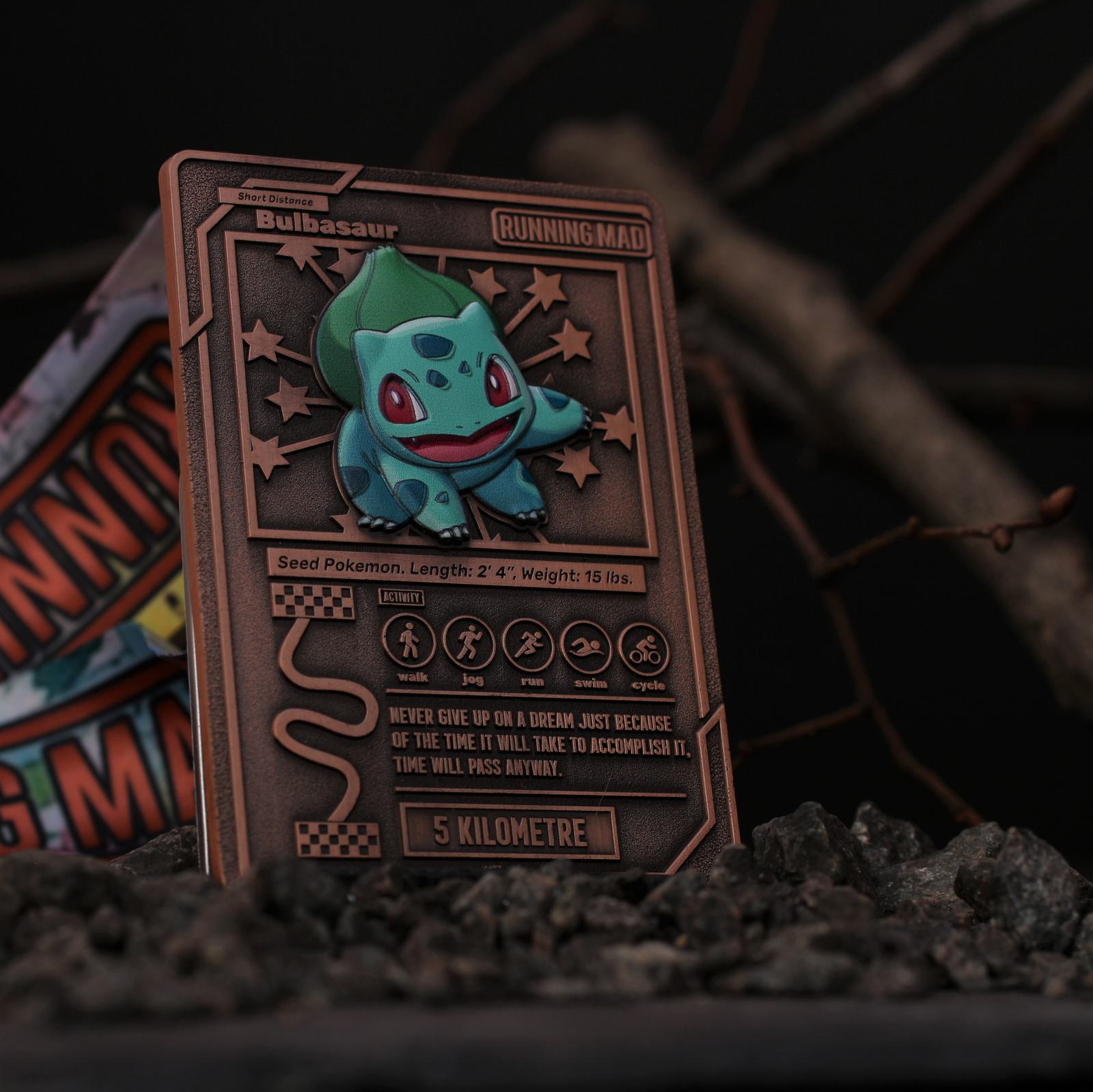 A Bulbasaur-themed card with "Running Mad" theme, adorned with stars and stats like seed, length, weight, and a motivational quote. The card rests on dark, rocky soil with twigs in the background.