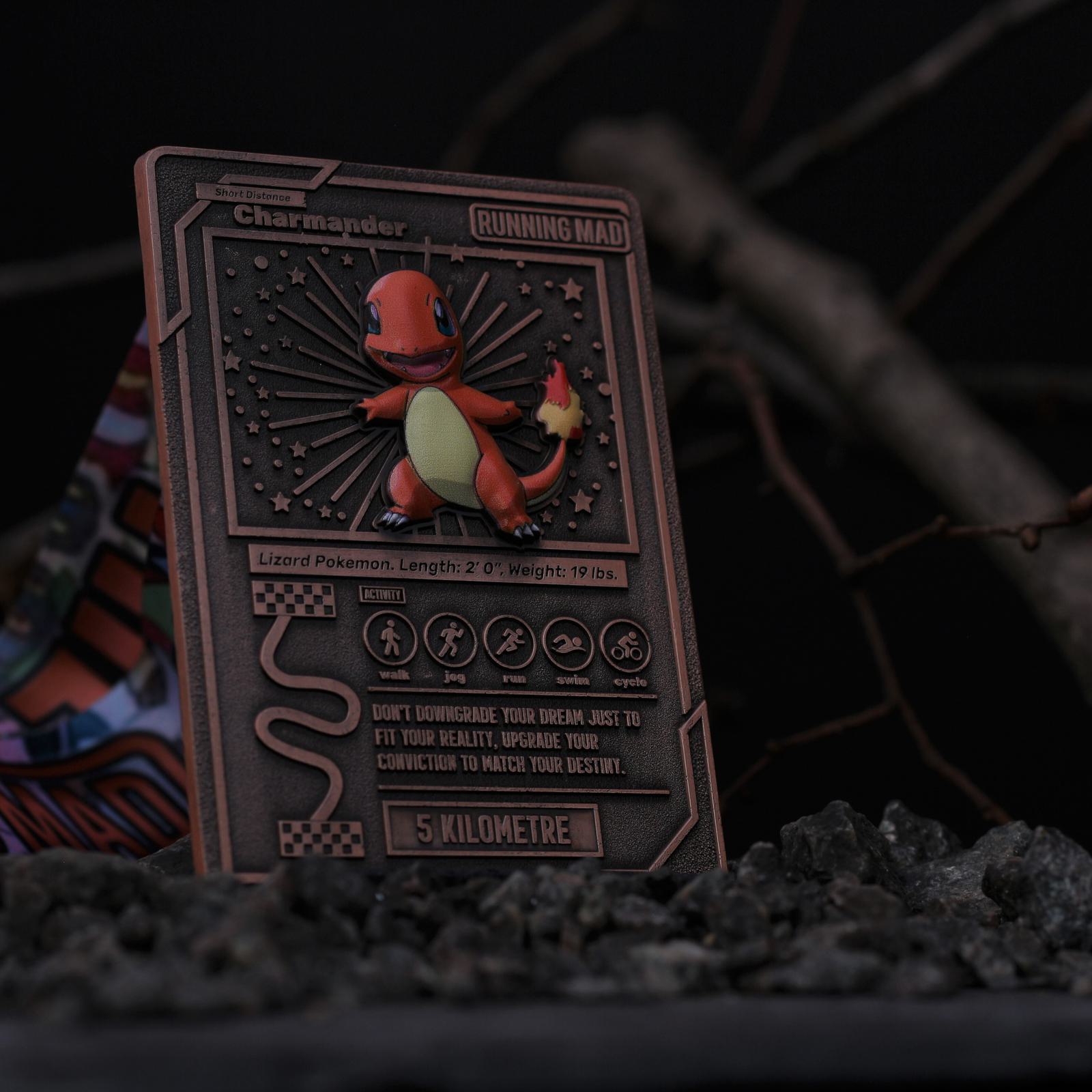 A close-up of a card featuring Charmander, a lizard Pokémon. The card has stars and stripes in the background and displays information about Charmander, such as length, weight, and a motivational quote. It's set against a dark, rocky backdrop.
