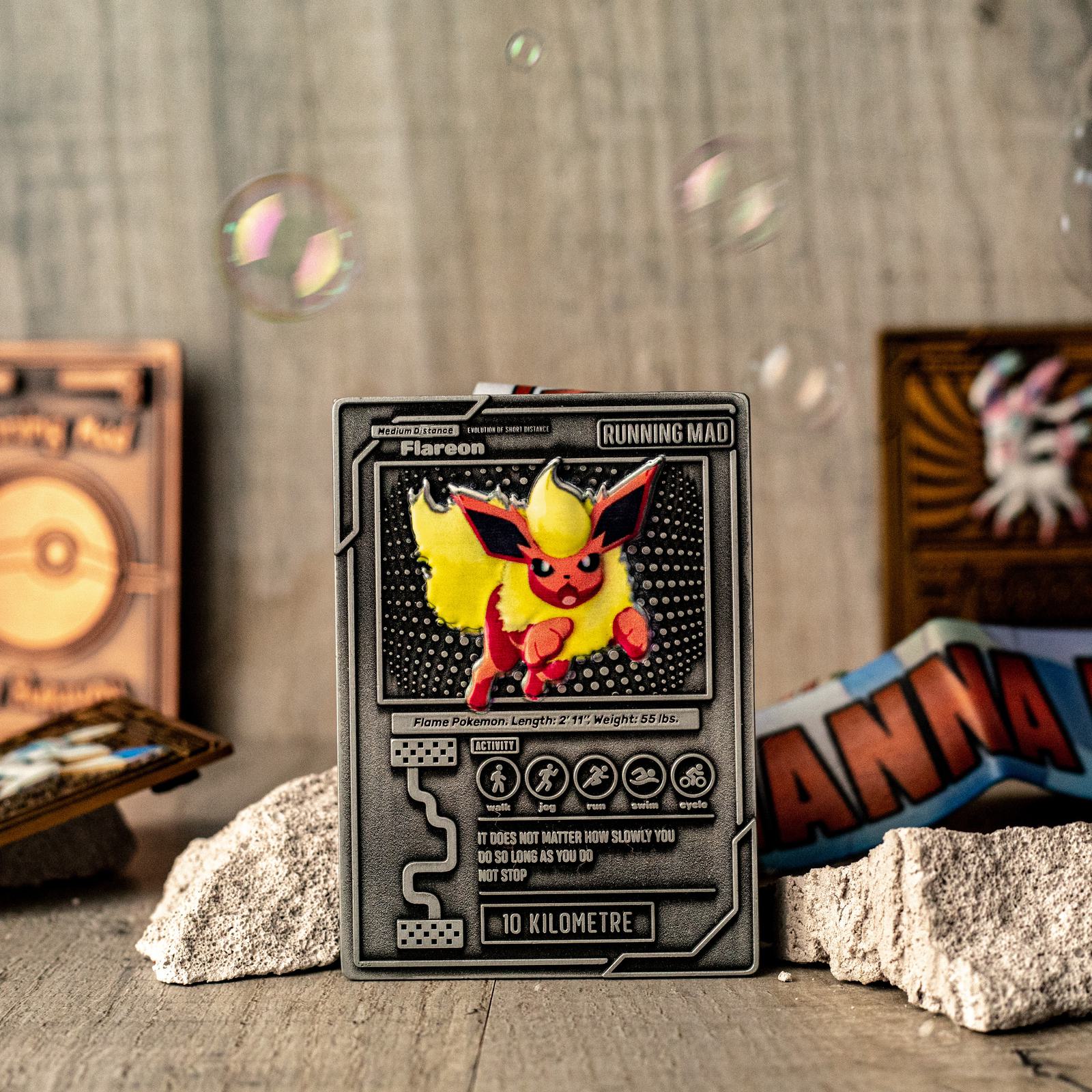 A Flareon card displayed upright on a textured surface, surrounded by small rocks. In the background, colorful card backs and soap bubbles are visible against a wooden backdrop, adding a playful and dynamic atmosphere.