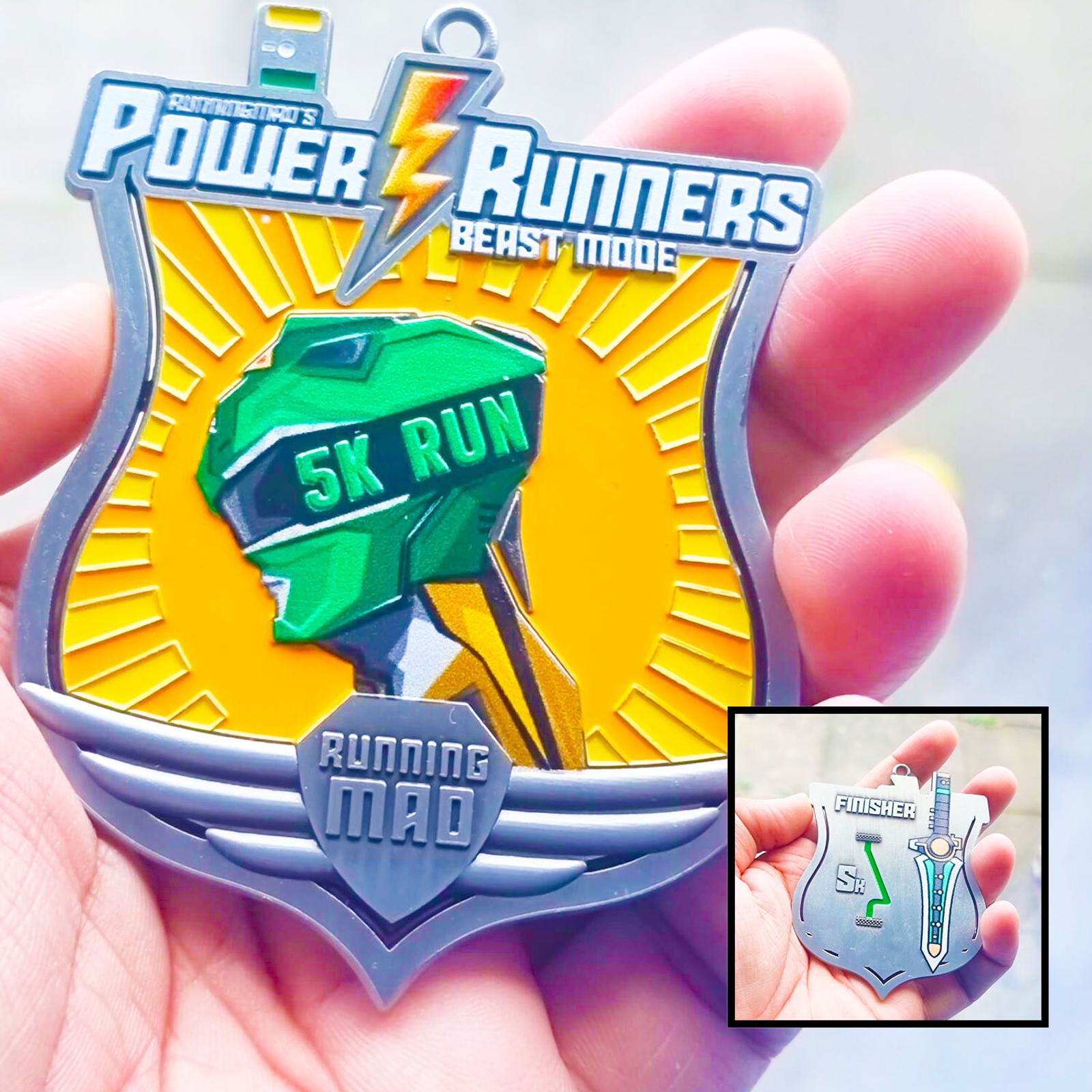 Close-up of a person holding a medal shaped like a shield. The medal reads "Power Runners Beast Mode 5K Run" with a stylized runner’s head. Inset image shows the backside labeled "Finisher" with a smaller logo. Background is blurred.