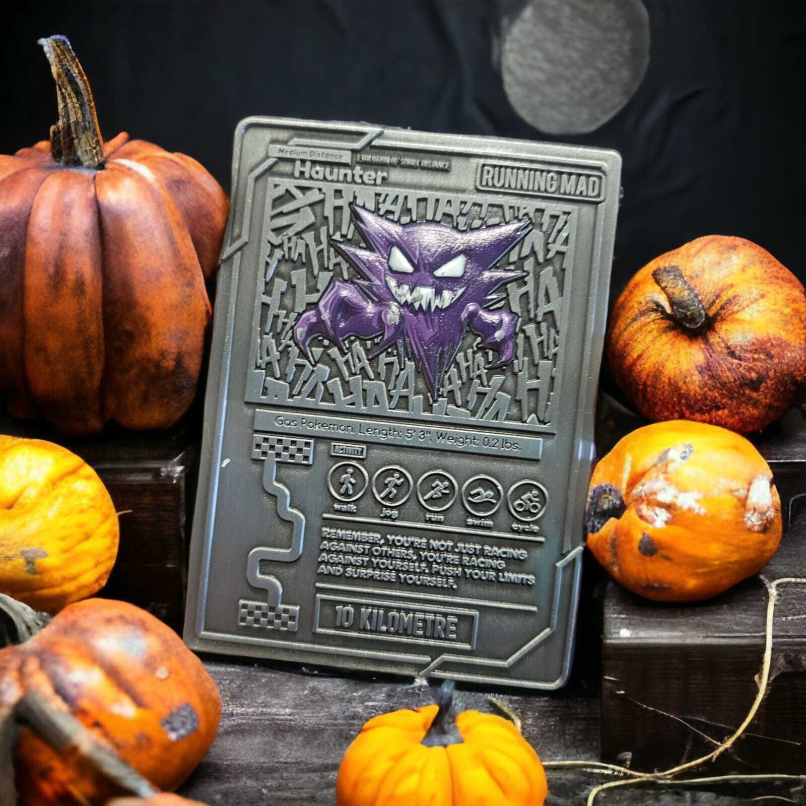 A Halloween-themed medal featuring a spooky purple character with sharp eyes and claws, surrounded by pumpkins in various sizes. The text on the medal reads "Haunter Running Mad 10 Kilometre." It has an intricate design with a metallic finish.