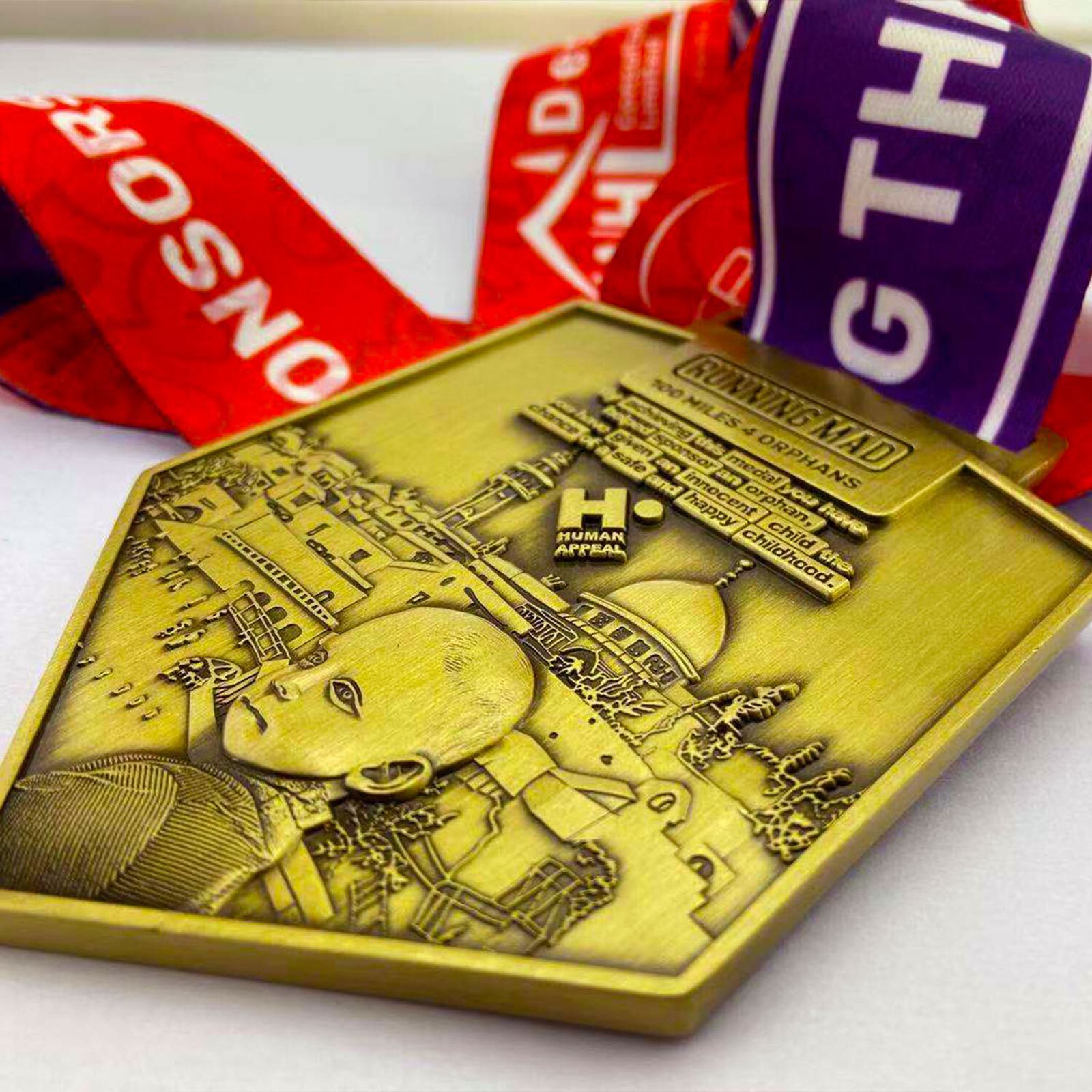A gold-colored, hexagonal medal with engraved cityscape and a face design. It features the text "Running Mad" and "Human Apparel" with a red and purple ribbon attached.