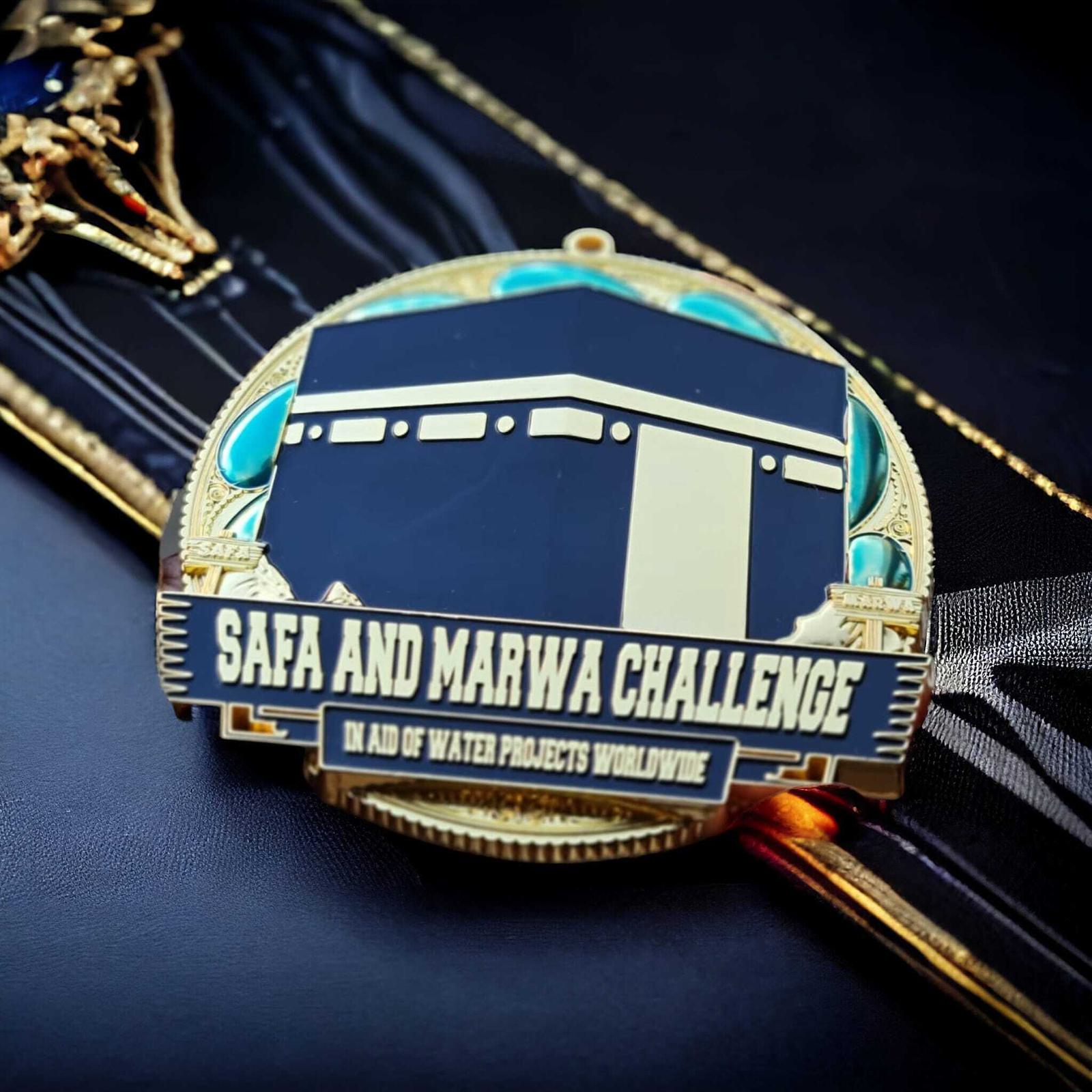 A medal with an image of the Kaaba and the text "Safa and Marwa Challenge in Aid of Water Projects Worldwide" rests on a ribbon with a gold and black design.