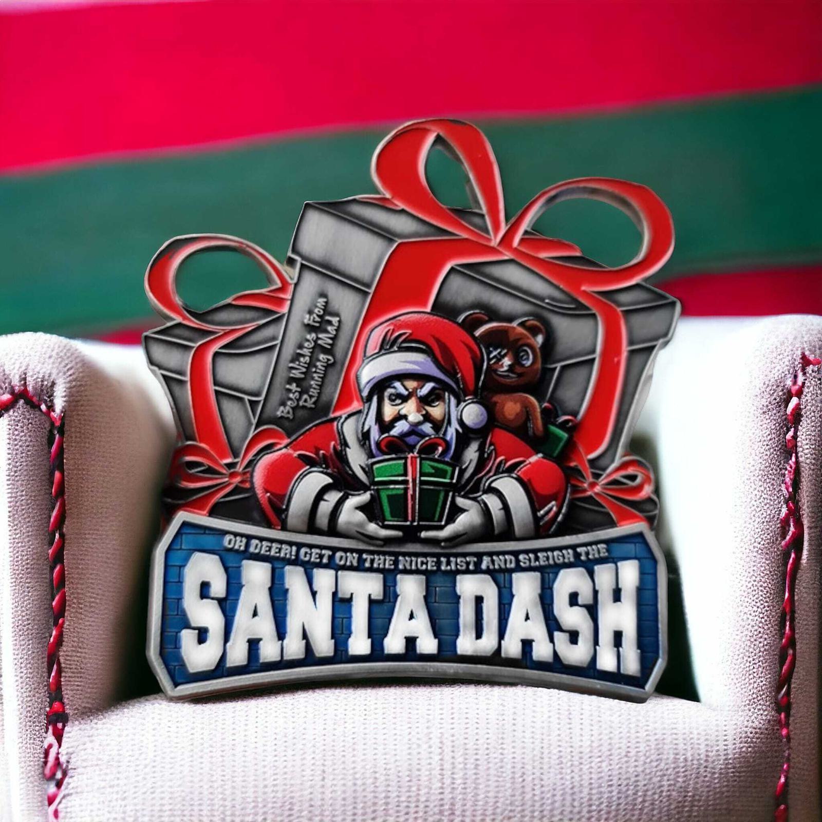 A festive medal featuring Santa holding a green gift, with two red-ribboned presents and a teddy bear in the background. The text reads "Santa Dash" and "Oh deer! Get on the nice list and sleigh the.