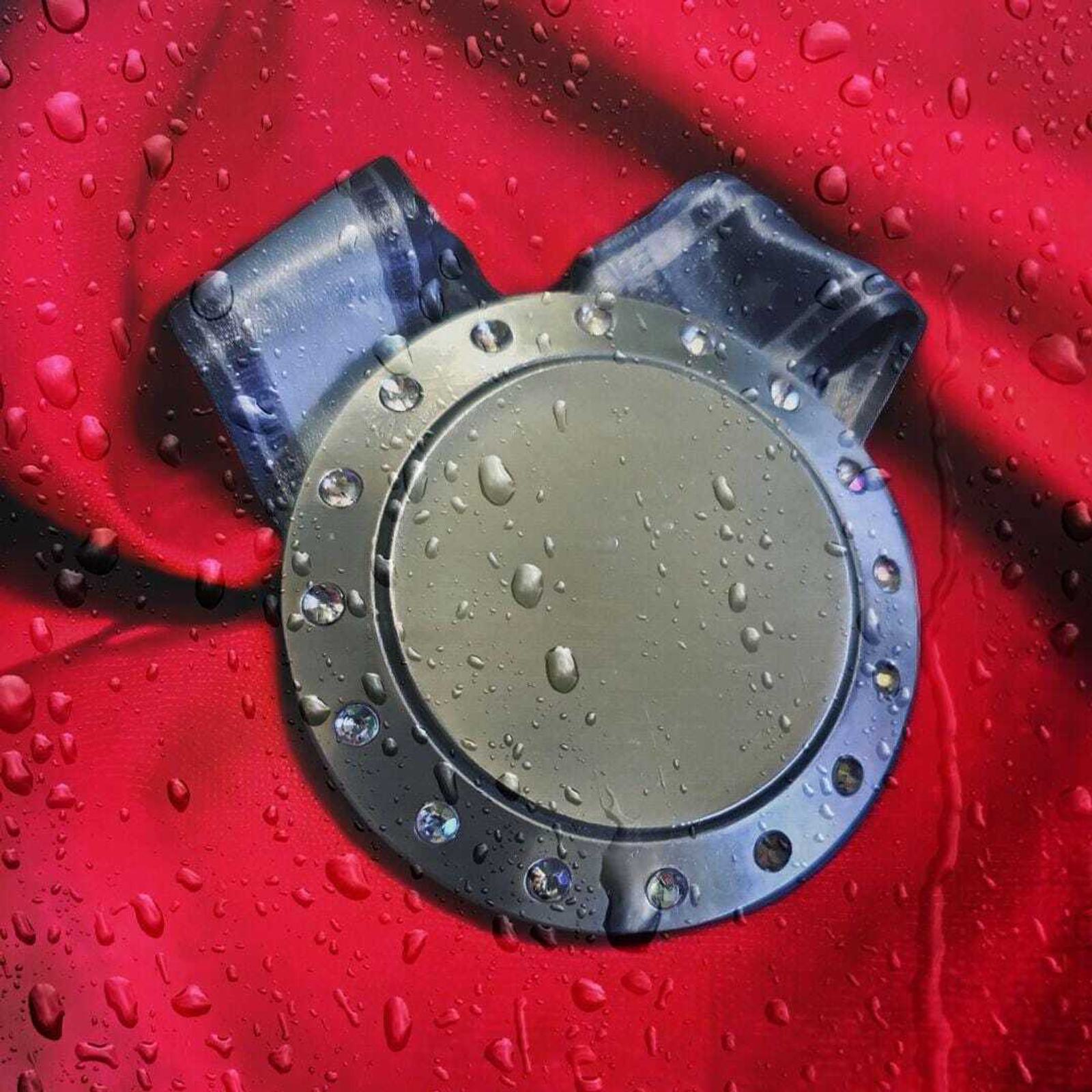 A metallic circular object with small studs, resembling a belt buckle, is set against a red fabric background. Water droplets are scattered on the object and fabric, giving a fresh and wet appearance.