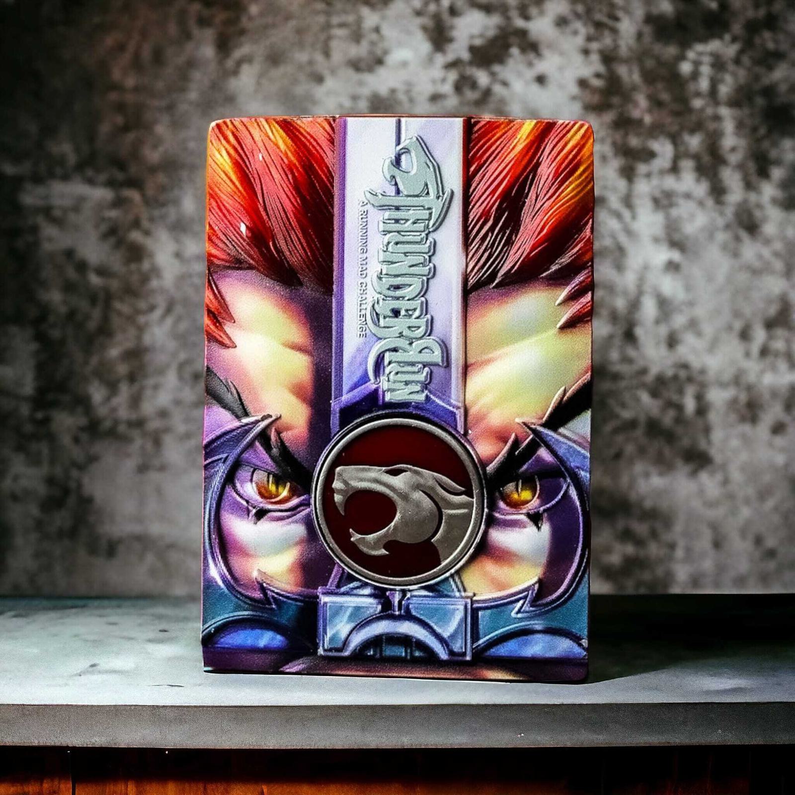 A colorful collectible card featuring a dramatic close-up of an illustrated character with bright red hair and intense eyes. The design includes a silver emblem depicting a roaring feline. The background is a textured gray surface.