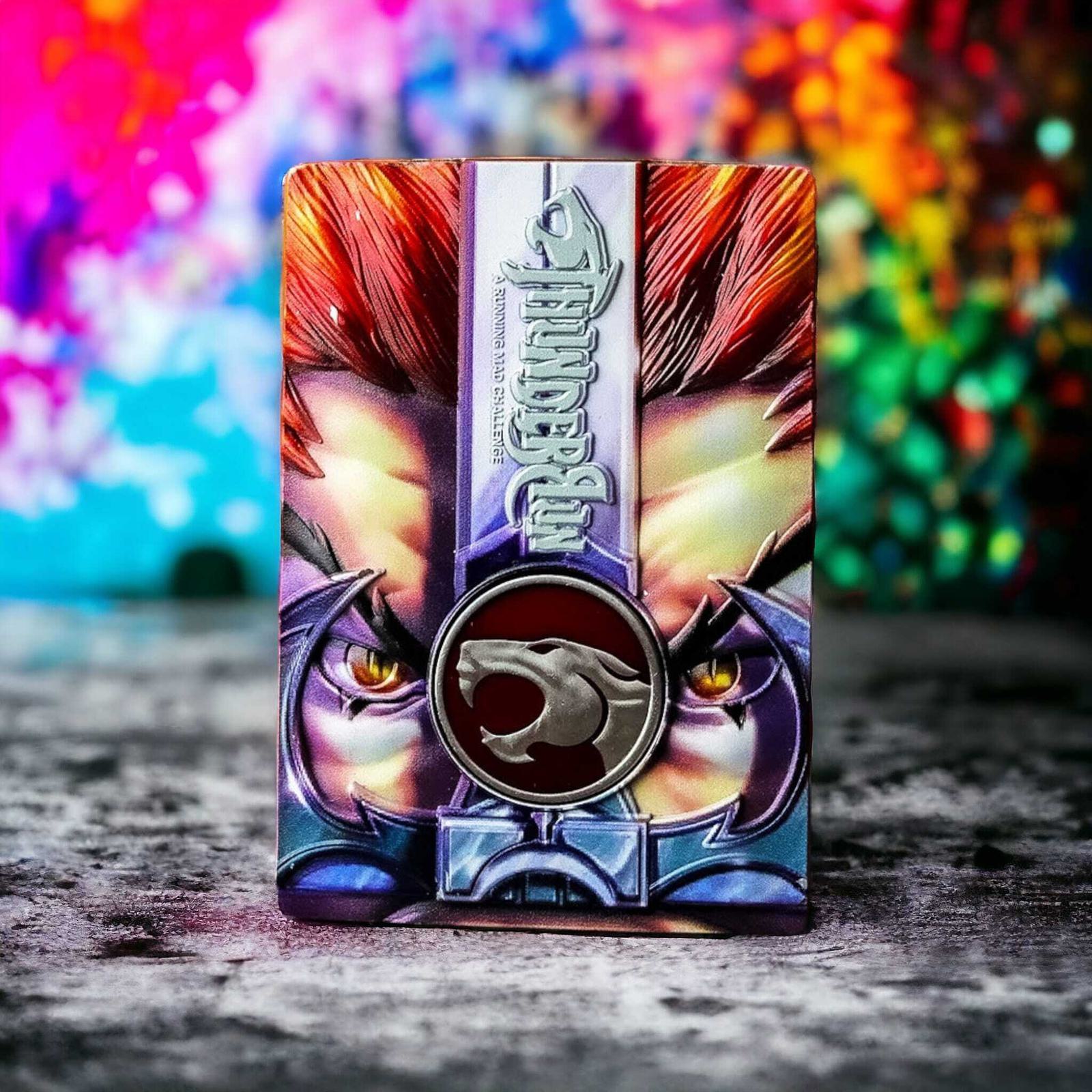 A vibrant card features a striking close-up of intense eyes with red and white hair. Below is a silver emblem with a cat silhouette. The background is an explosion of colorful hues, creating a dynamic and dramatic contrast.