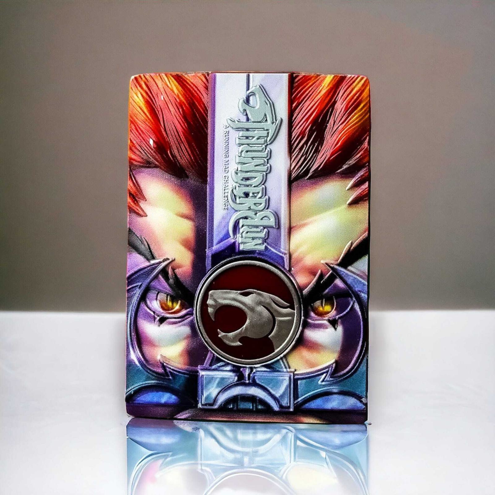 A vibrant, illustrated box features a fierce, stylized face with red hair and prominent eyes, accented by a metallic emblem of a roaring cat on the front. The design is dynamic and colorful, set against a plain background.