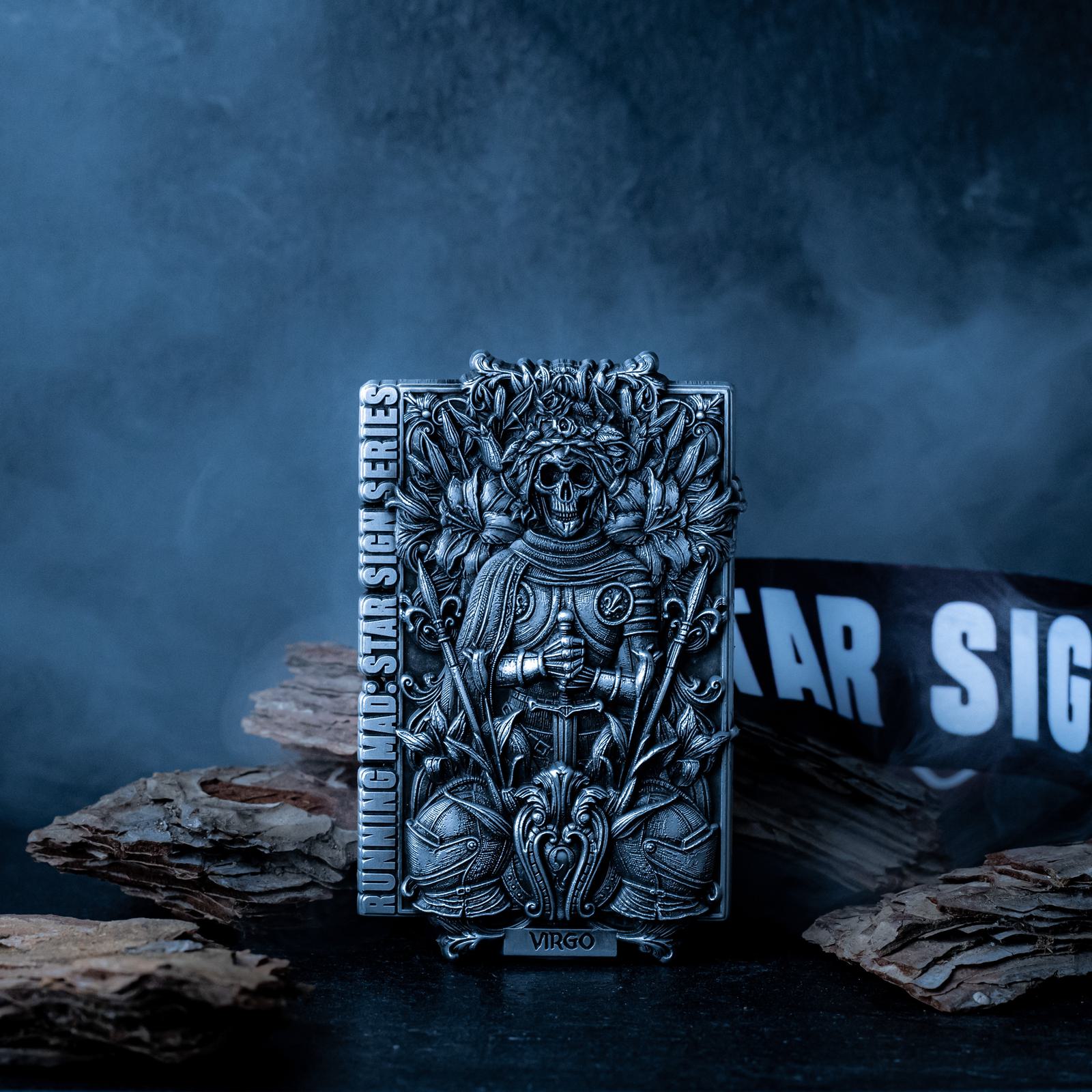 A detailed, ornate lighter with a skull and foliage design stands upright. It features the word "Virgo" at the base and is labeled "Running Wild Star Sign Series." It is set against a smoky, dark background with a partially visible banner.