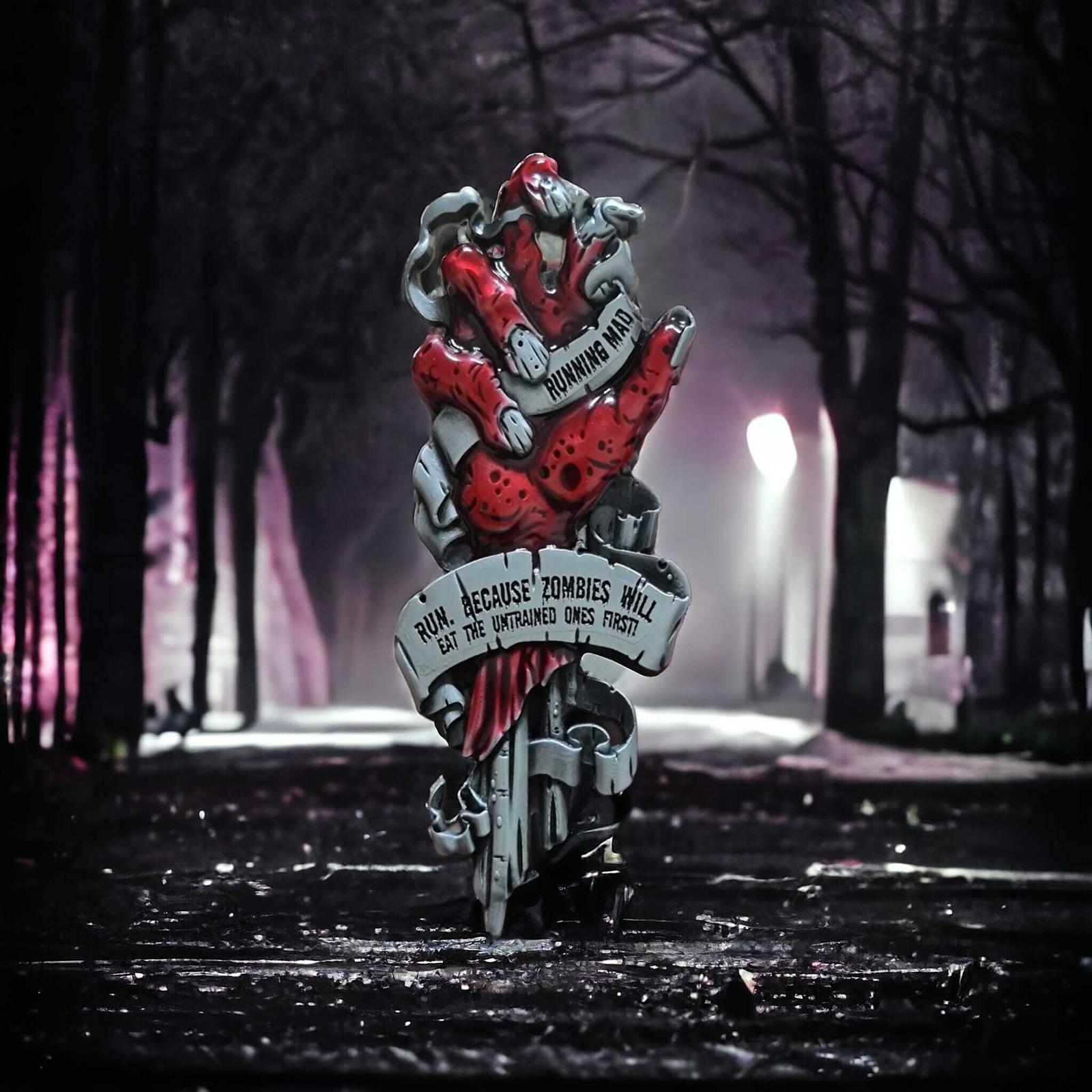 A eerie, foggy pathway in a dark forest, featuring a graffiti-style art piece with red zombie-like figures. A ribbon reads, "Run, because zombies will eat the untrained ones first." Dim streetlights cast an ominous glow.