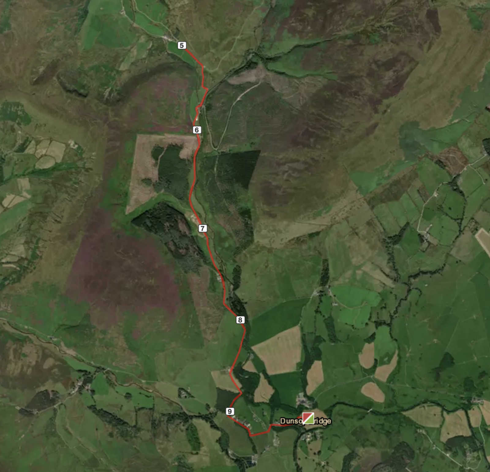 Satellite view of a hiking trail marked in red, winding through a lush green mountainous landscape. The route includes numbered waypoints starting from 5 and ending at 9 near Dunsop Bridge, with fields and forests surrounding the path.