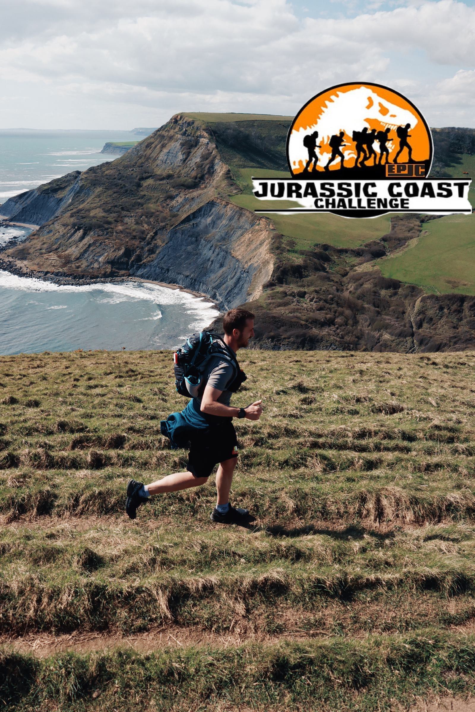 A person runs along a grassy hill with a scenic coastline in the background. The sky is partly cloudy. A circular logo with silhouettes of runners and text "Jurassic Coast Challenge" is overlaid in the top right corner.