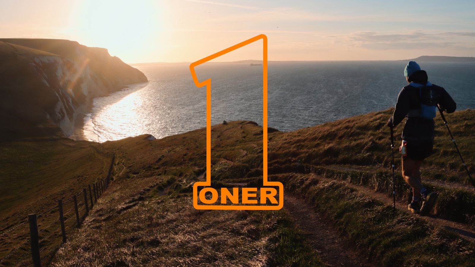 A person hiking on a cliffside trail at sunset, overlooking the ocean. The number "1" and the word "ONER" are prominently displayed in orange on the image.