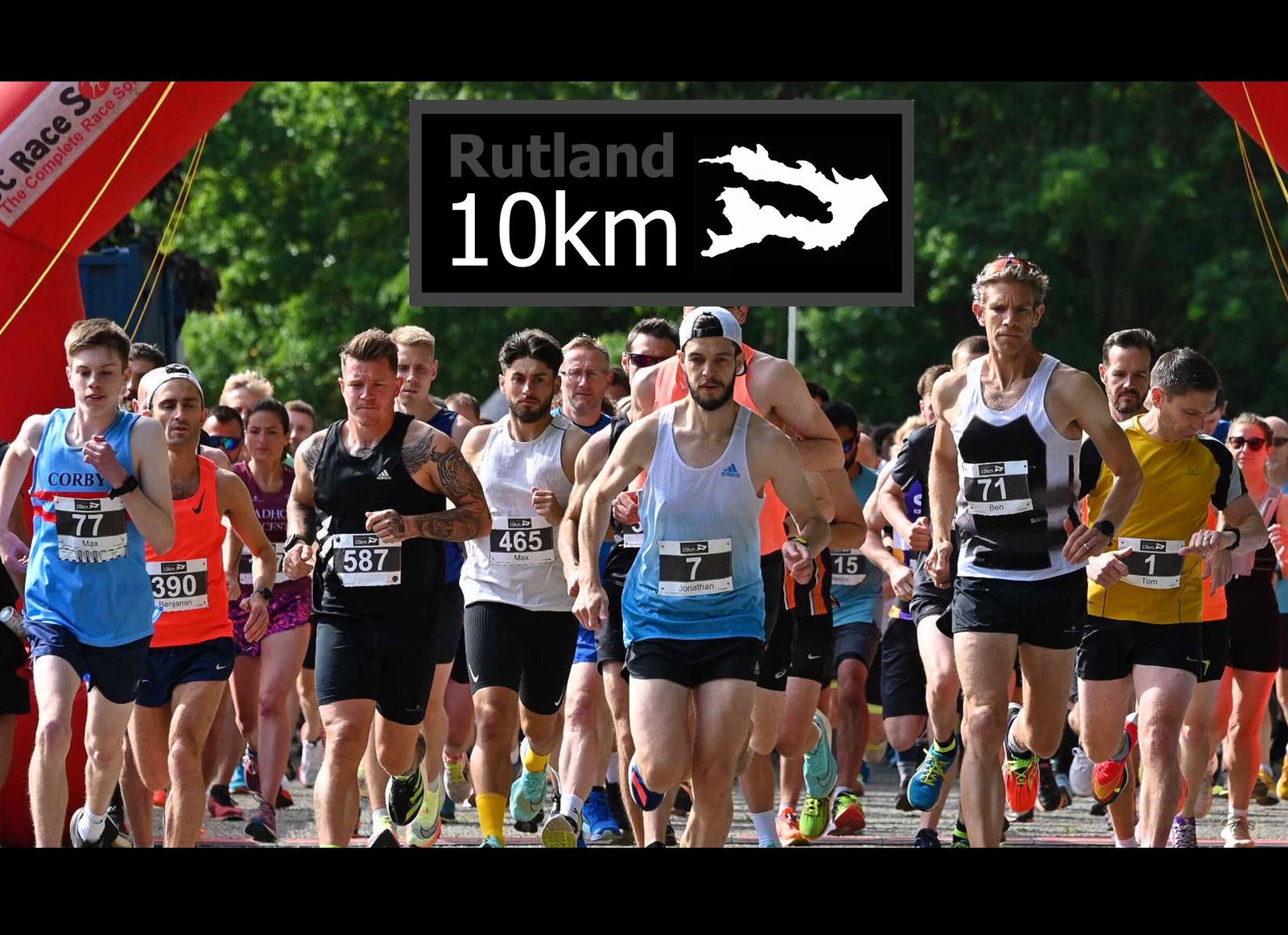 Runners in athletic gear begin a race at the Rutland 10km event, passing under a red inflatable arch. The group is diverse, with varied expressions of focus and determination, against a backdrop of greenery. A sign reads "Rutland 10km.