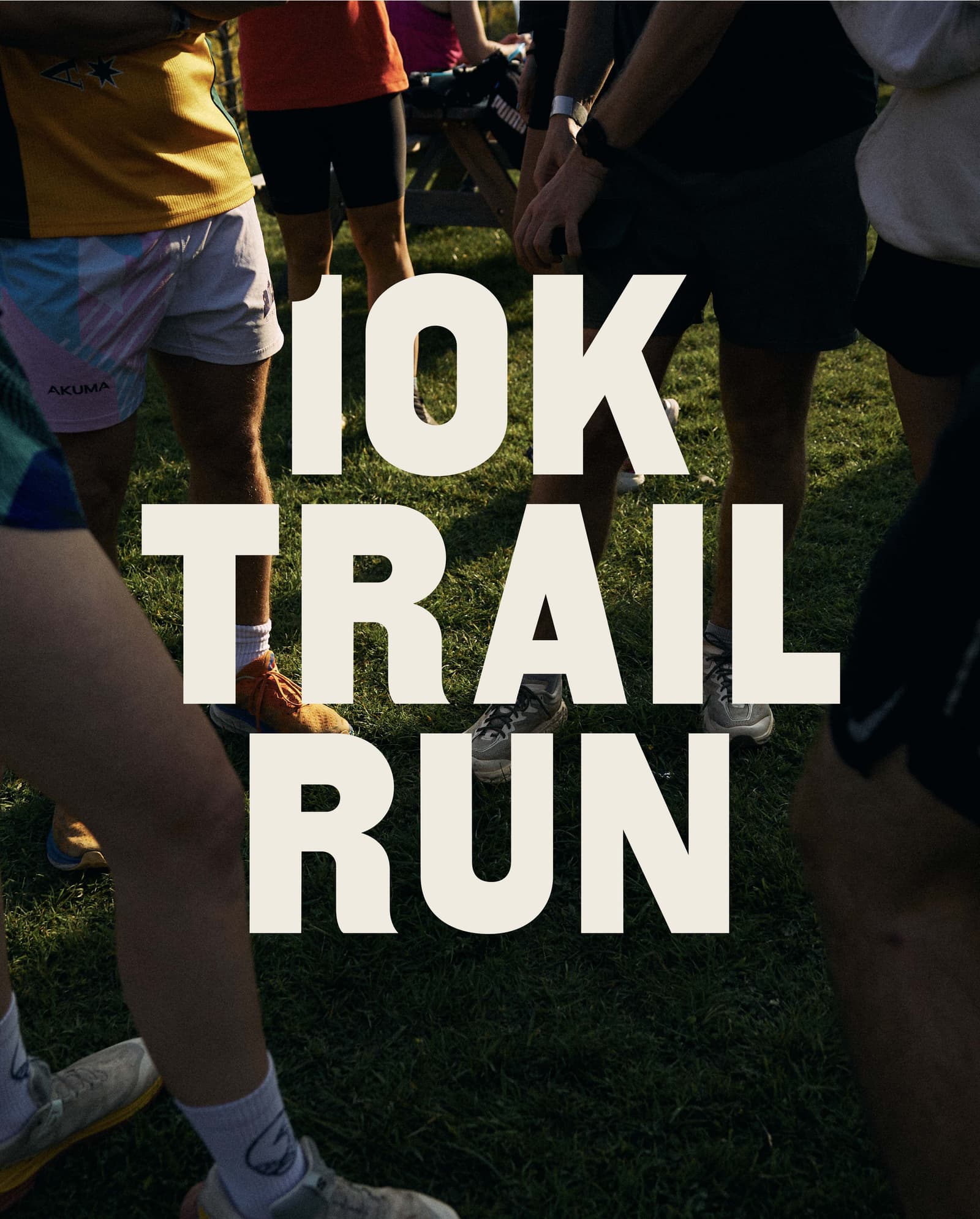 Several runners stand in a grassy area, only their legs visible, with large text overlay that reads "10K TRAIL RUN." The scene suggests preparation for a trail running event.