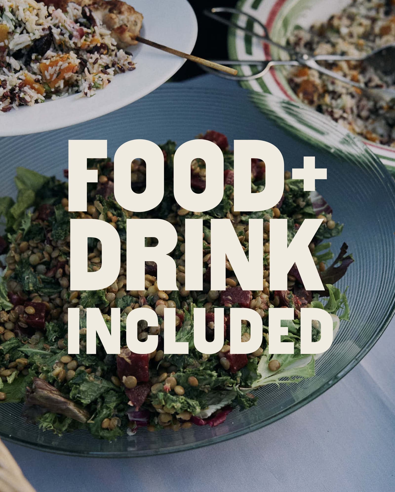A glass bowl of salad and plates of food on a table, with large white text over the image that reads "FOOD + DRINK INCLUDED.