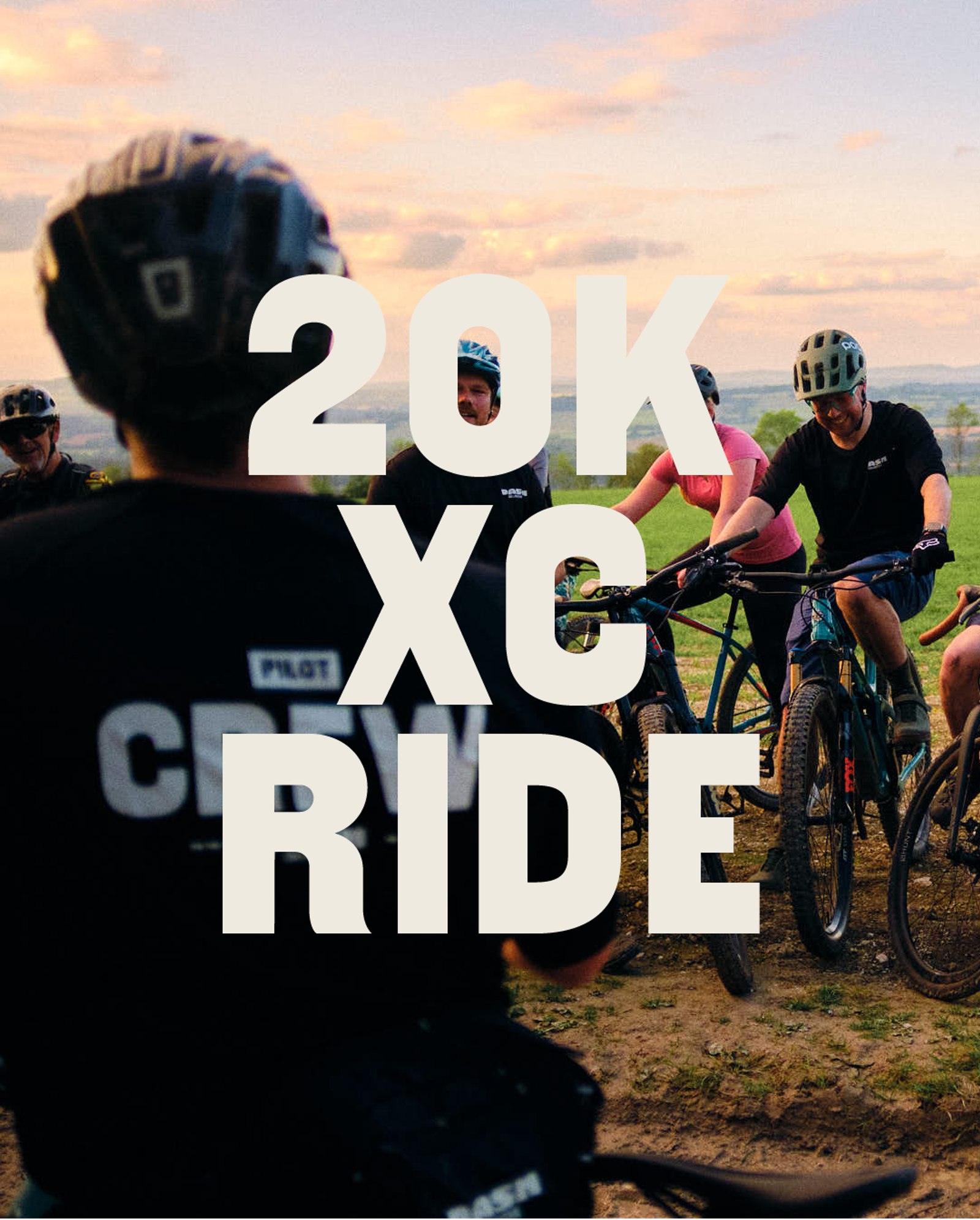 A group of cyclists wearing helmets and biking gear gather outdoors at sunset, smiling and chatting. Bold white text over the image reads: "20K XC RIDE.