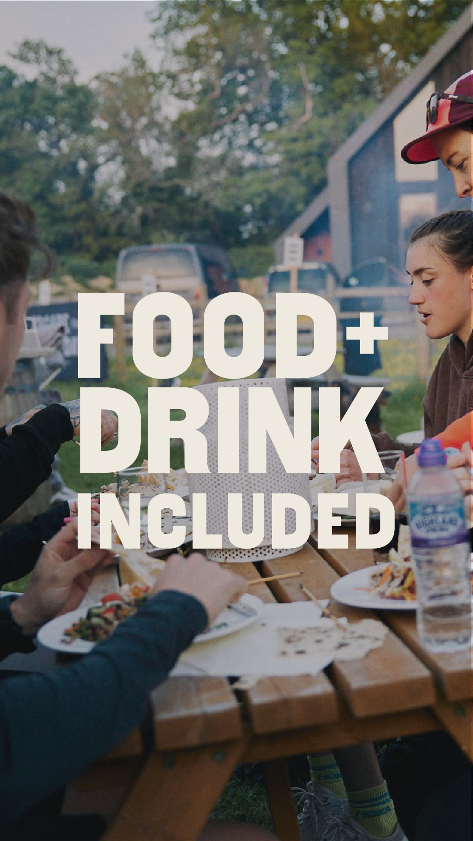 Four people sit around a wooden picnic table outdoors, eating food and drinking water. The text "FOOD + DRINK INCLUDED" is overlaid in bold white letters. Trees and a building are visible in the background.