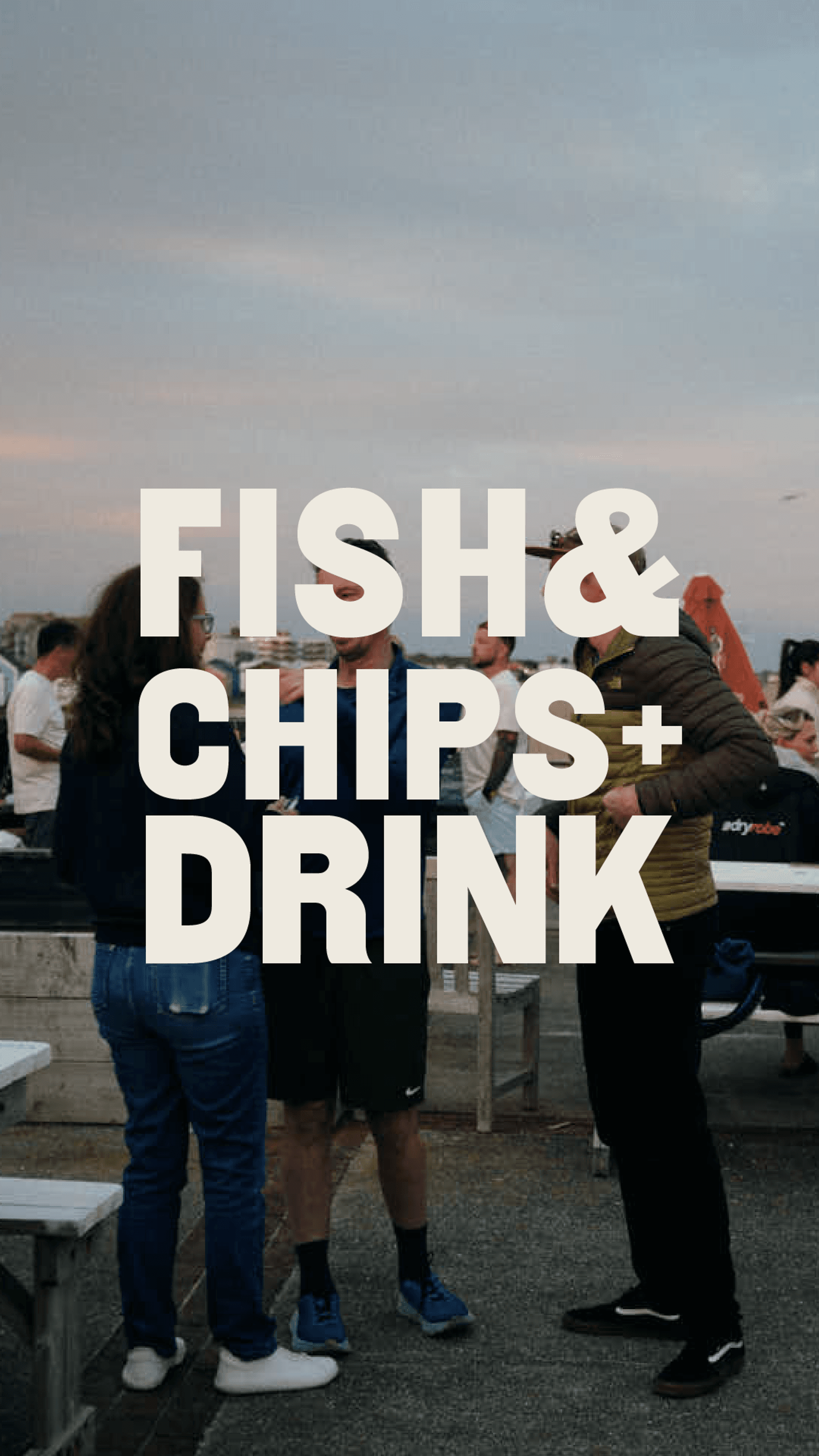 Three people stand outdoors near picnic benches at sunset, talking together. Large bold text in the center reads: "FISH & CHIPS + DRINK." Other people and a food stall are visible in the background.