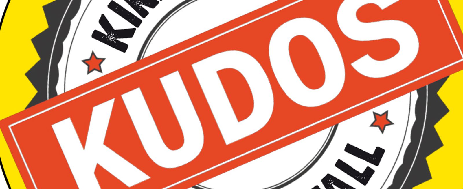 A circular badge with the word "KUDOS" in large white letters on a red banner across the center, with stars, and partially visible words "KIND" and "FULL" around the edges.