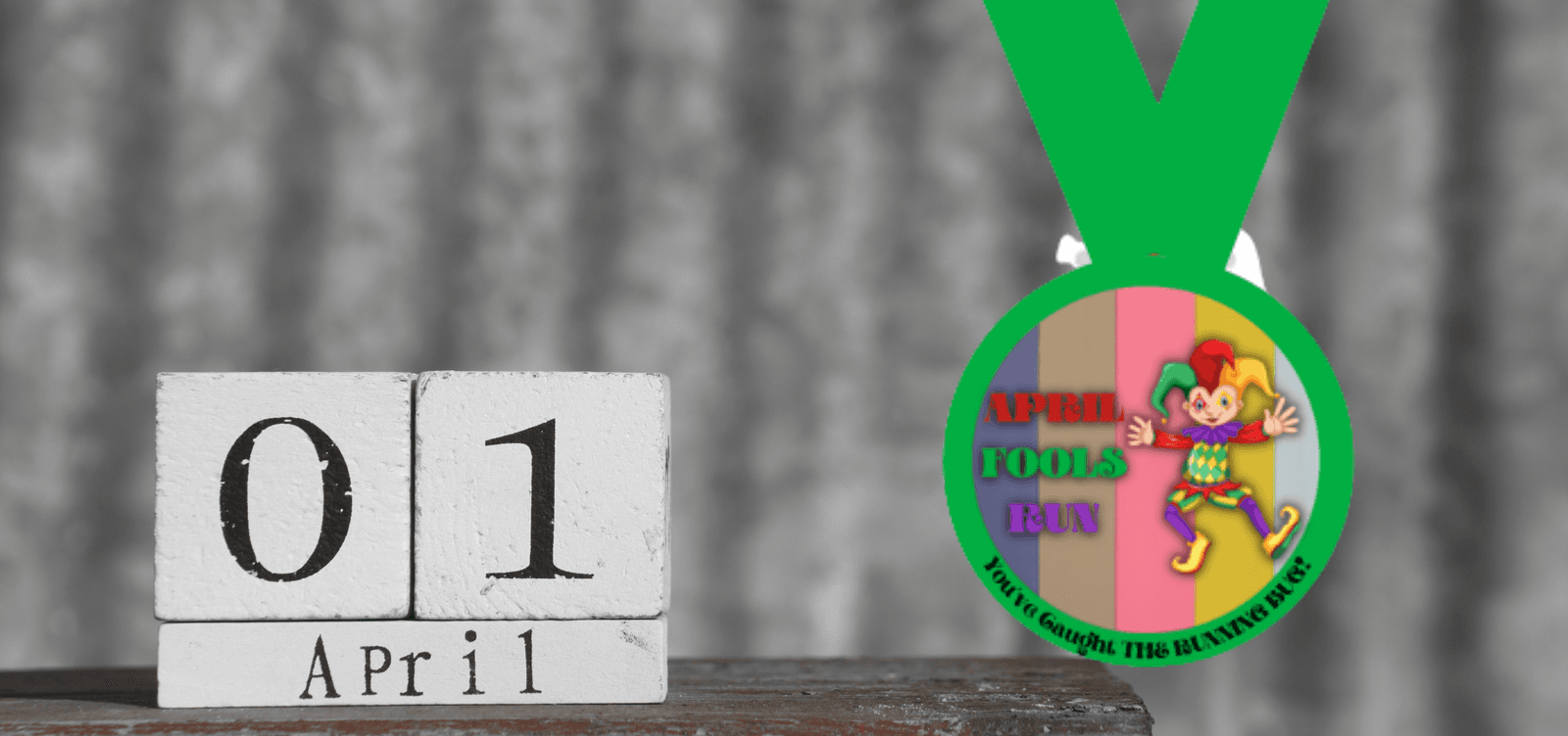 A desk calendar displaying "01 April" on wooden blocks is in the foreground. A colorful medal hangs nearby, with a jester and the words "APRIL FOOLS RUN" on the front, and text saying "5K/10K RUN-SPRINT WALK" along the bottom edge of the medal.